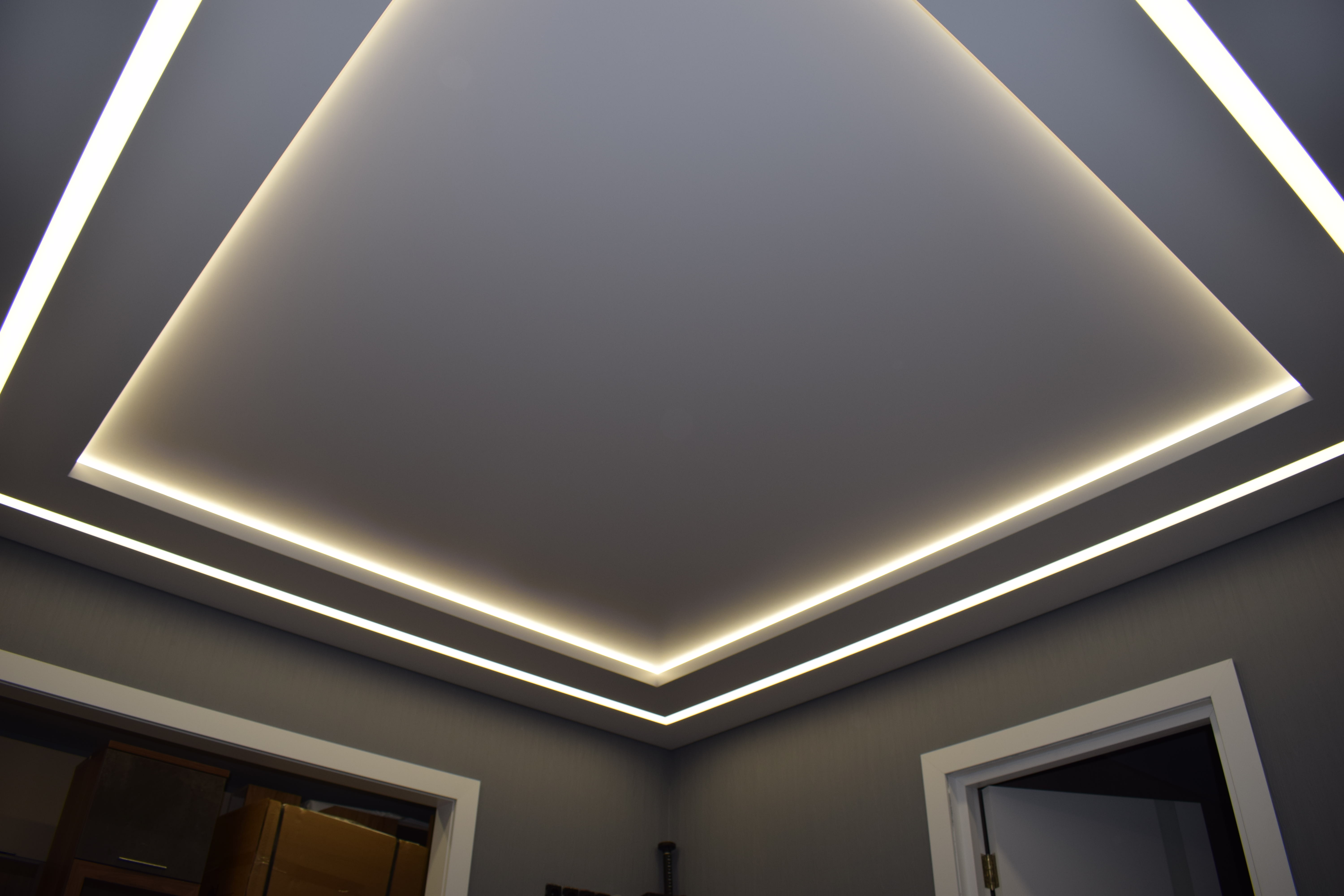 Двухуровневый натяжной потолок с подсветкой в нише и световой линией в гостиной 